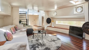 A modern living room with a sofa, a round coffee table, and a large window with a view.