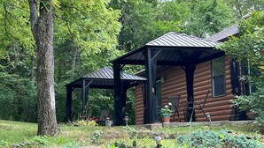 A rustic cabin with a covered porch and a garden area. - Walnut Waters Bed & Breakfast (Lone Jack)