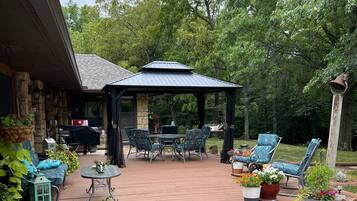 Un patio cubierto con mobiliario exterior, un sendero de piedra y un jardín con diversas plantas y flores.