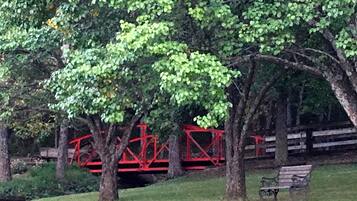 A park with trees, a red bridge, and a bench.