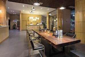 A modern reception area with a wooden reception desk, a long conference table with chairs, and pendant lighting. - Youmi Hotel (Changde)
