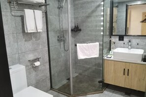A modern bathroom with a glass-enclosed shower, a white sink, and a wooden cabinet. - Youmi Hotel (Changde)