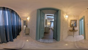 A hallway with a curved ceiling, a marble floor, and a mirror on the right wall.