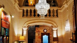 A grand lobby with a chandelier, a fireplace, a coffee table, and a sofa.