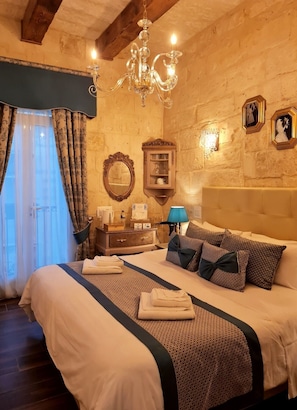 A bedroom with a large bed, a chandelier, a dresser, a mirror, and a wall-mounted cabinet.