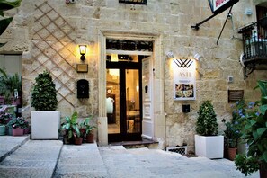 A stone building with a door open, potted plants, and a sign that reads "HUB".