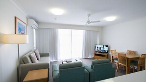 A modern living room with a sofa, two armchairs, a coffee table, a TV, and a dining area with a table and chairs. - Beachcomber Beach, Coolangatta (Coolangatta)