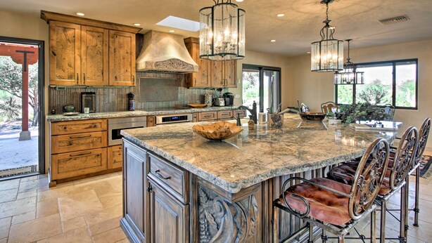 A spacious kitchen with a large island, wooden cabinets, and a modern chandelier. - Luxe Tucson Vineyard Home w/ Views & Fire Pit (Tucson)
