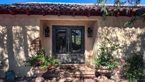 A traditional building with a tiled roof, a double door with decorative ironwork, and potted plants on either side of the entrance. - Luxe Tucson Vineyard Home w/ Views & Fire Pit (Tucson)
