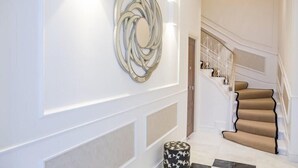 Ein modernes Interieur mit Treppe, Wanddekoration und einem gemusterten Hocker.
