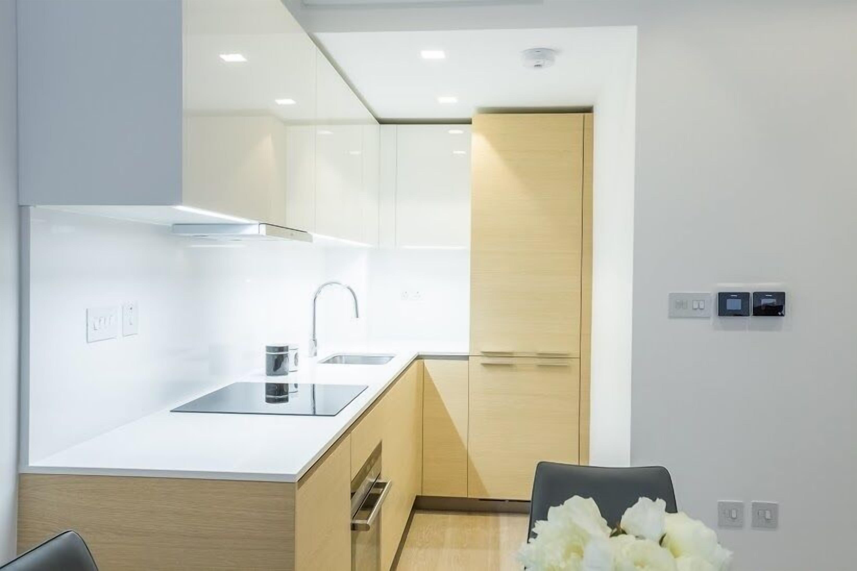 A modern kitchen with a sink, countertop, and wooden cabinets.