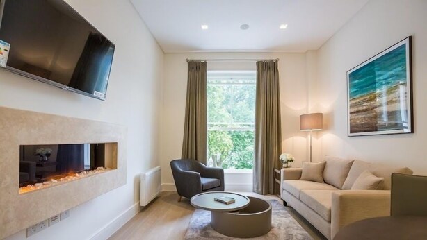 Ein modernes Wohnzimmer mit Kamin, Flachbildfernseher, Sofa, Couchtisch und Lampe.