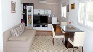 Un salon avec un canapé, une table à manger avec des chaises, un coin cuisine avec des placards et un téléviseur.