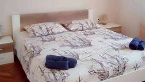 Un lit avec une couvre-lit et des oreillers aux motifs marins, une lampe de chevet et des serviettes enroulées posées sur le lit.