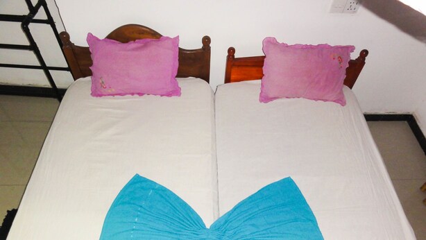 A bed with a wooden headboard, two pillows, and a large decorative bow on the bedspread. - Spring holiday (Mirissa)
