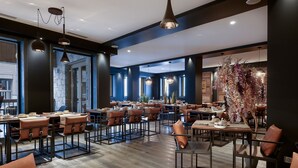 A modern restaurant with high ceilings, pendant lighting, and a mix of leather and metal furniture. - Whistler Lodge Apartment T3 Cabin B07 (Courchevel)