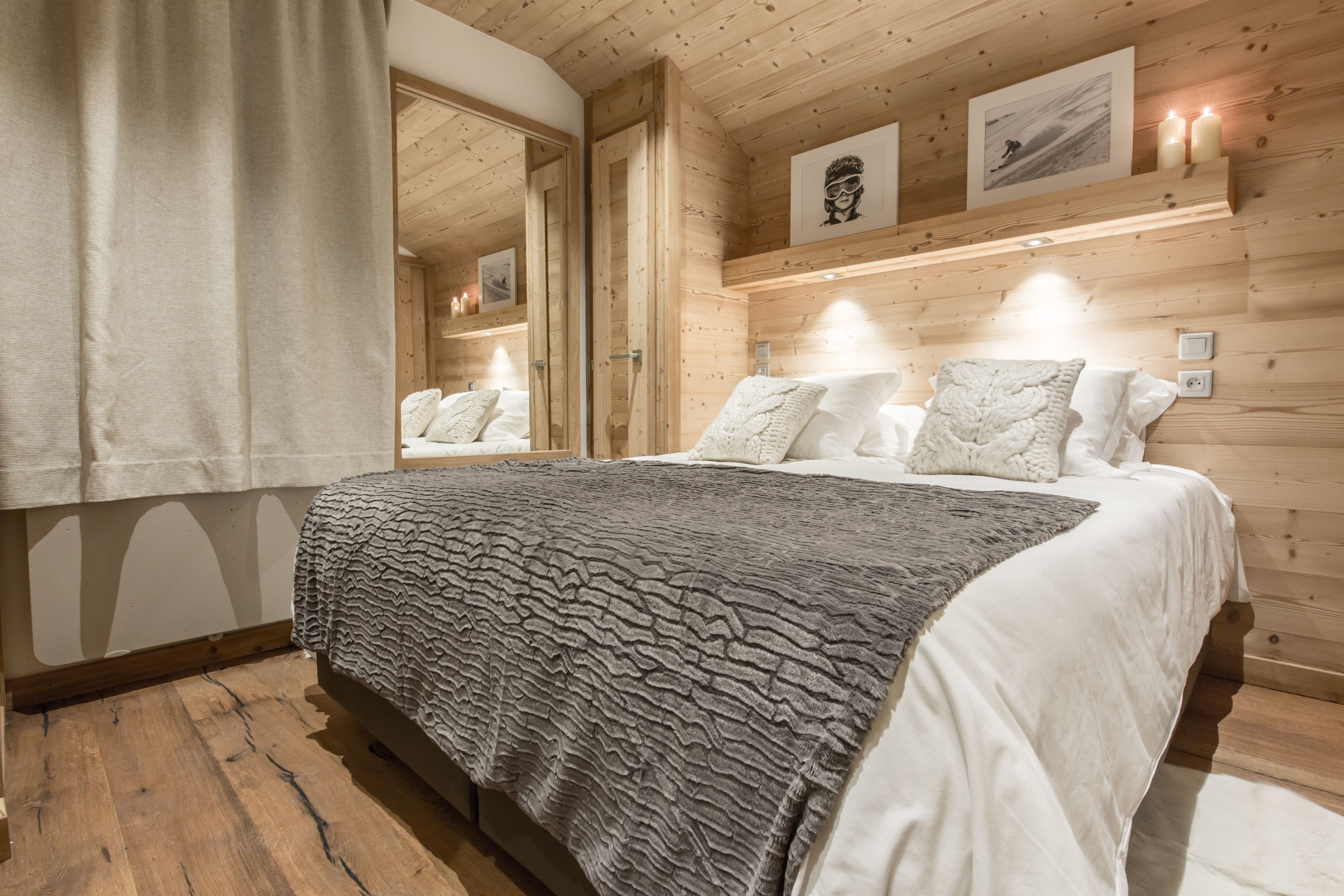 A wooden-paneled bedroom with a large bed, white bedding, and framed artwork on the wall.