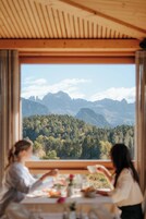 Una habitación con un ventanal grande que da a una extensa cadena montañosa boscosa.