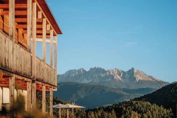 Una cabaña de madera con un balcón que da a una cadena montañosa.
