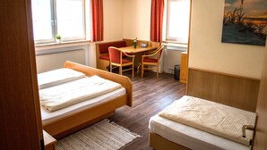 A room with two beds, a dining table, and a chair. - Zum Ochsen (Waldstetten)
