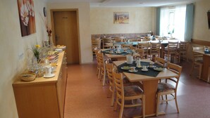 A dining area with multiple tables and chairs, a buffet setup on the left, and a private door. - Zum Ochsen (Waldstetten)