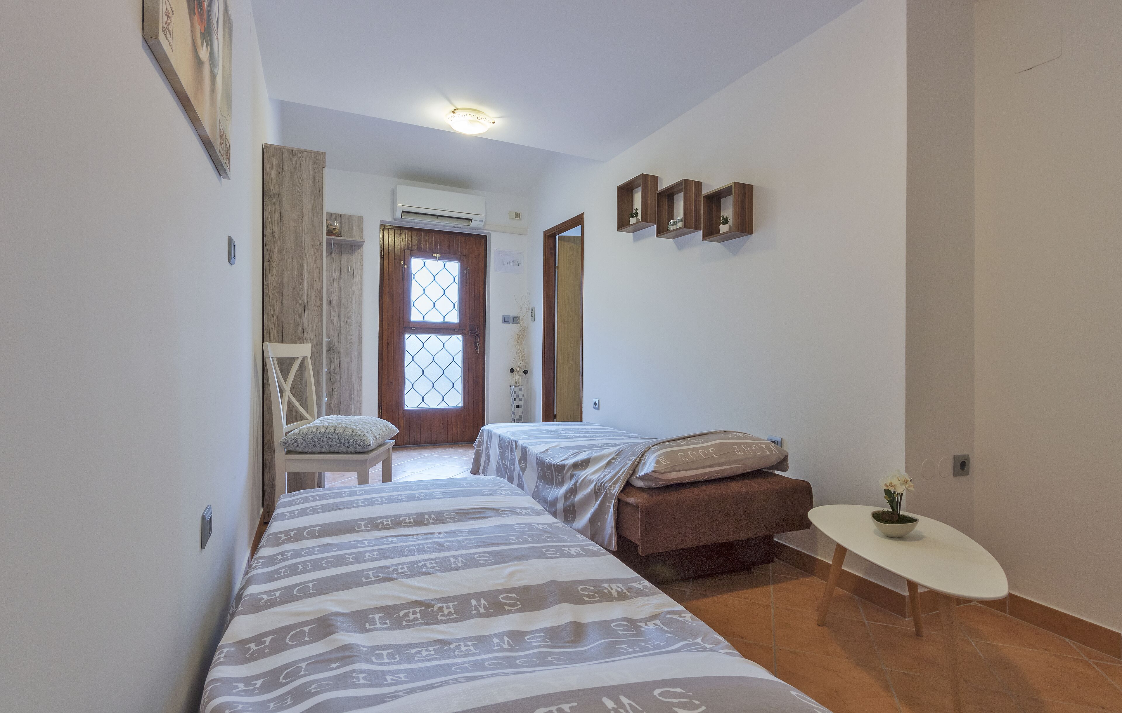 Une petite chambre avec deux lits, une petite table et une chaise.