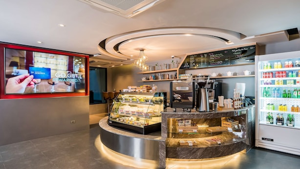 Ein modernes Café mit einer gebogenen Theke, einer Kaffeemaschine und einem Getränkeautomaten.