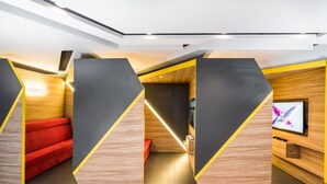 Ein modernes Interieur mit geometrischen Wandpaneelen, einem roten Sofa und einem Flachbildfernseher.