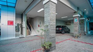 Un vestíbulo moderno con un pilar de piedra, plantas en macetas y un coche estacionado en su interior.