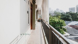 Un balcón estrecho con vistas a un paisaje urbano y zonas verdes.