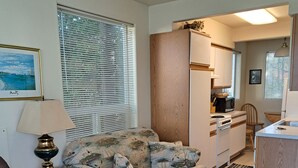 Un espace de vie compact comprenant un canapé, une table à manger et une kitchenette.