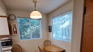 Une cuisine compacte comprenant une table et des chaises, un four à micro-ondes et une horloge murale.