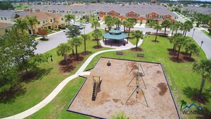 A residential area with a playground, a gazebo, and a row of houses.
