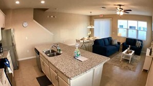 A modern kitchen with granite countertops, a built-in sink, and a dining area with a table and chairs.