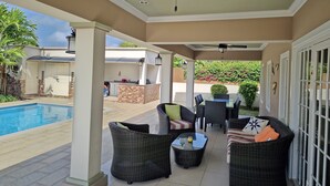 Un'area patio coperta con piscina, mobili da esterno e una ventola a soffitto.