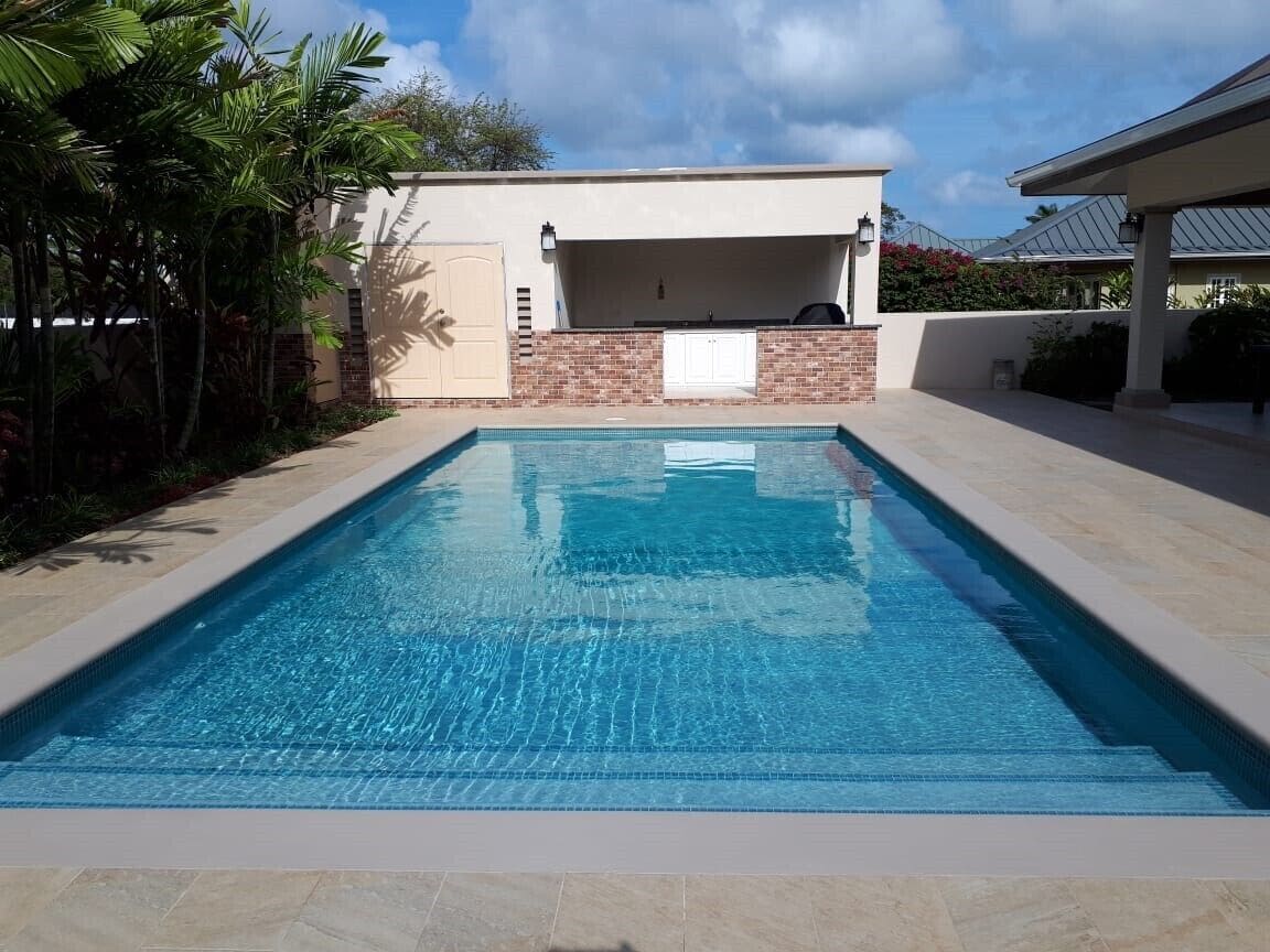 Une piscine rectangulaire à l’eau d’un bleu limpide, entourée d’une terrasse carrelée.