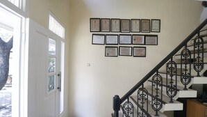 A staircase with a black iron railing, a white door with glass panels, and a wall with framed certificates. - RedDoorz @ Jalan Gatot Subroto Jakarta (Jakarta)