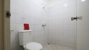 A bathroom with a toilet, a shower, and a tiled floor. - RedDoorz @ Jalan Gatot Subroto Jakarta (Jakarta)
