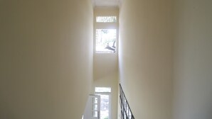 A narrow hallway with white walls and a door at the end. - RedDoorz @ Jalan Gatot Subroto Jakarta (Jakarta)