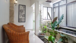 A modern interior with a wicker chair, a potted plant, and a framed artwork on the wall. - RedDoorz near Jogja City Mall (Pogung Lor)
