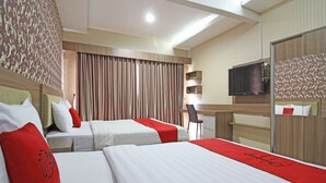 A hotel room with two beds, a desk, a chair, a television, and a wardrobe. - RedDoorz near Jogja City Mall (Pogung Lor)