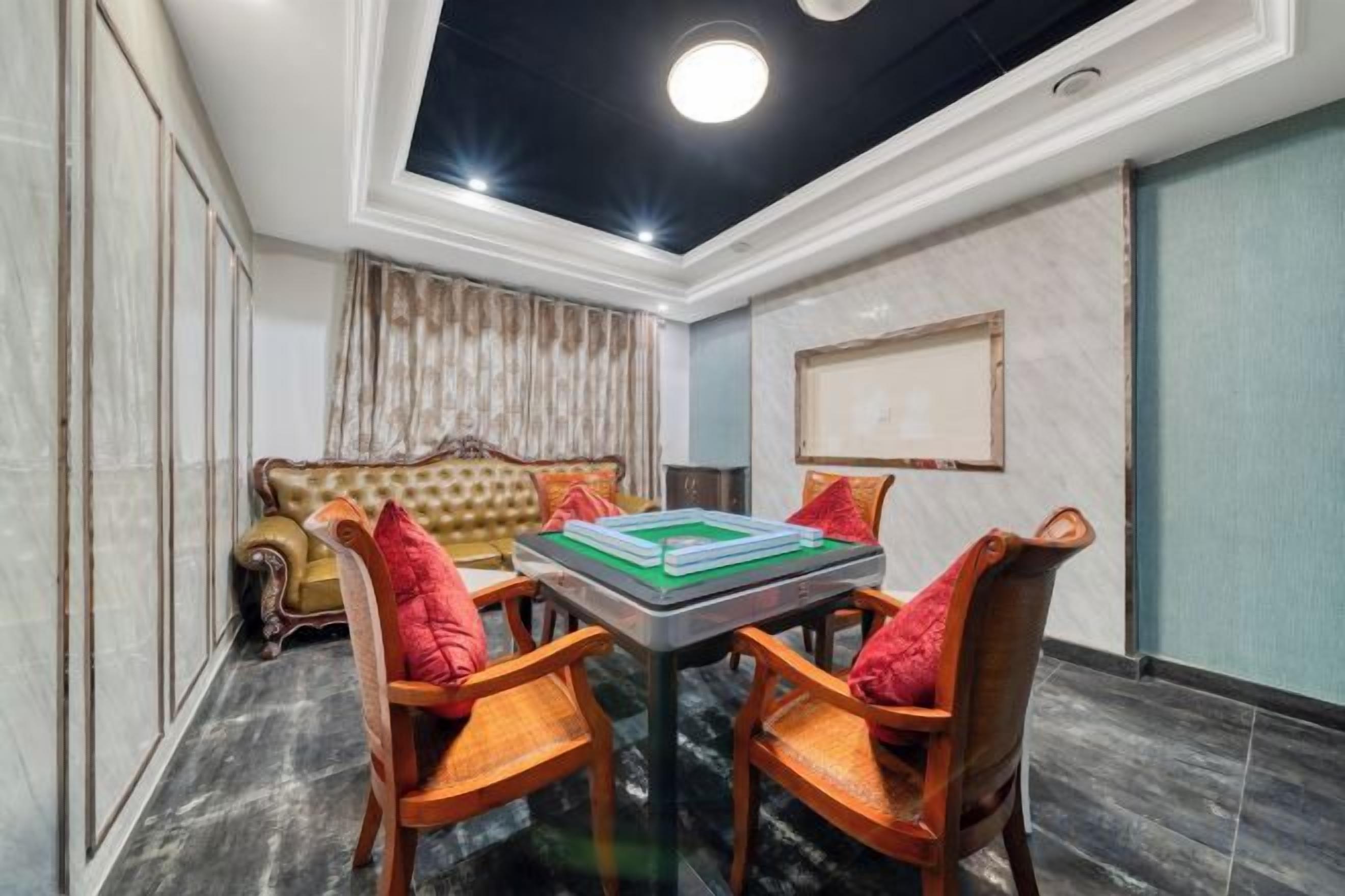 A room with a sofa, two chairs, a table, and a ceiling light.