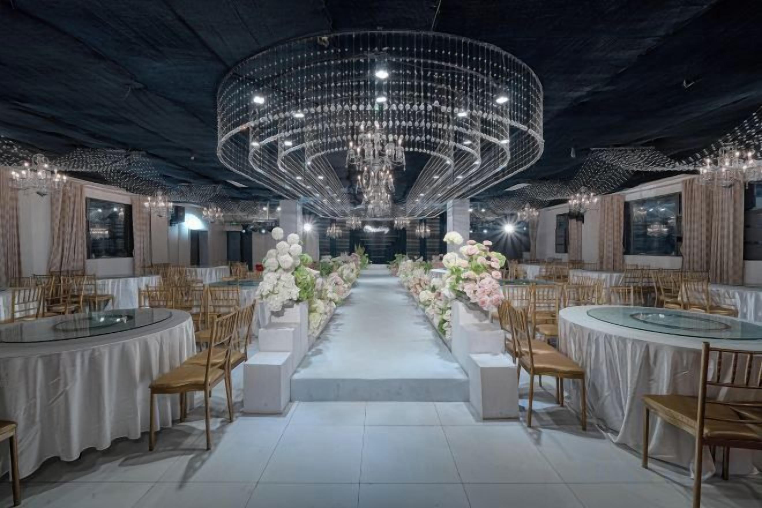 A banquet hall with round tables, chairs, and a central aisle.