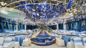 A banquet hall with tiered seating, a central stage, and a ceiling adorned with hanging decorations.