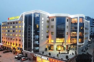 Un hotel de varios pisos con diseño moderno, que destaca por su entrada principal y un estacionamiento al frente.