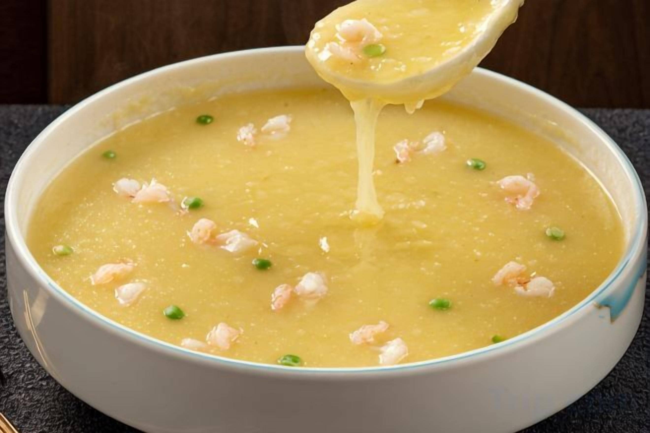 Un bol de sopa amb gambes i guarnició verda.