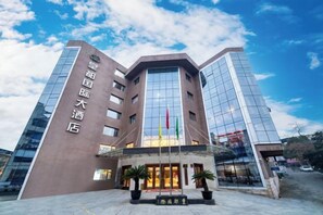 A hotel with a modern architectural design, featuring a prominent glass facade and a traditional entrance with a flag display.