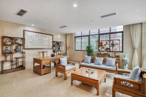 A traditional-style living room with furniture, a large window, and decorative items. - Huangdu International Hotel (Jiange)