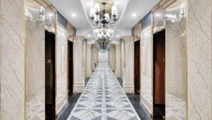 A hallway with marble walls and a geometric patterned floor, leading to a door at the end.