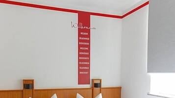 Ein Hotelzimmer mit einem hölzernen Bett, weißer Bettwäsche, einer roten Akzentwand und einem Fenster.